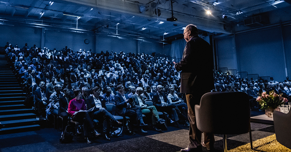 Göran Lindsjö på scen framför stor publik på Position för digitalt samhällsbyggande 2030